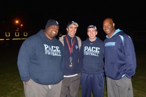 Coach Clemont Rouviere (second from left) gathers with fellow Pace football coaches at the bonfire on Dec. 3.
