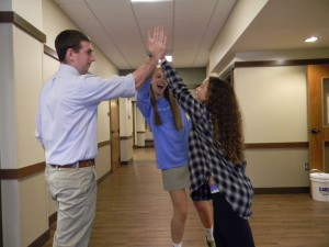 Students Mary Brooks Perkey and Zoe Weitzner excitedly high-five Mr. Sandoe as they discuss their trip to Vietnam.